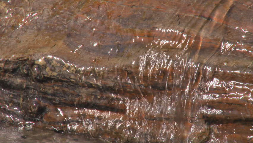 Red striated rock forms a ledge over which a freshet ripples
