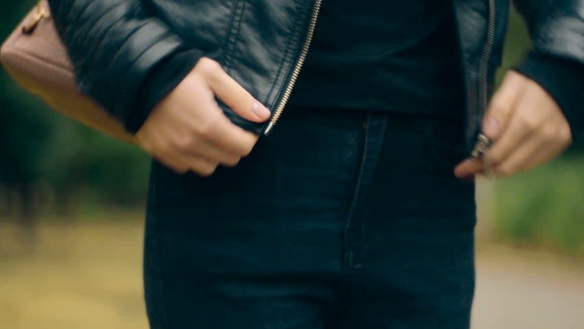 girl fastens a leather jacket in the street