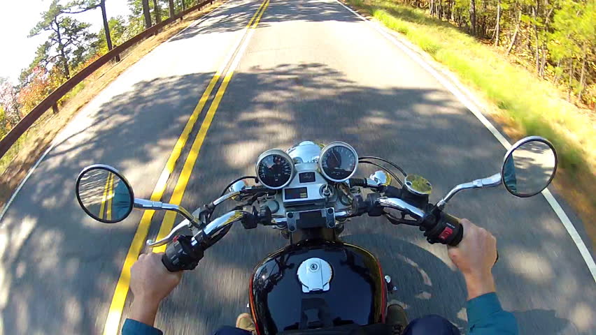 A high angle point of view shot from a motorcycle traveling down a forested
