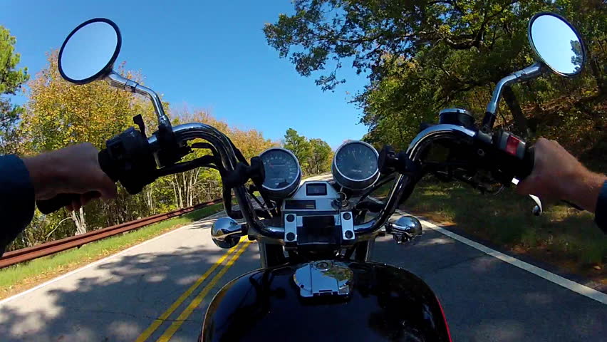 A wide angle shot of the point of view of someone riding a motorcycle on a curvy