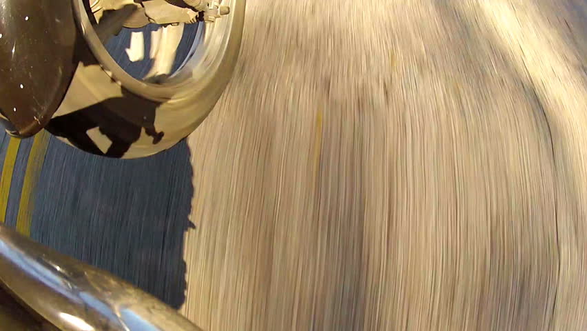 A close up shot of the road whizzing by beneath a speeding motorcycle.