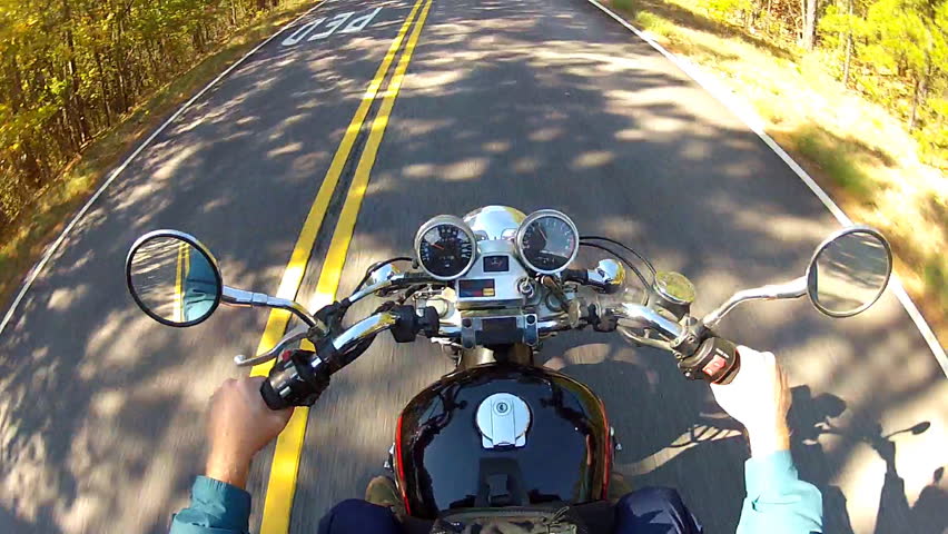 A shot of the handlebars, gages and gas tank of a speeding motorcycle as seen