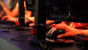 A lot of teenagers playing on computer games. Close-up of hands with keyboards and mouses.