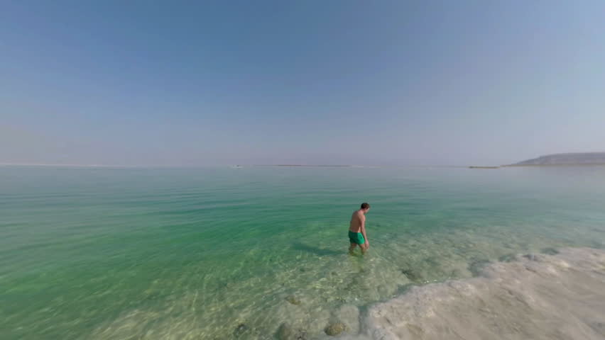 Man enjoying bathing in clear water of Dead Sea. Recreation resort in Israel. Skyline seascape