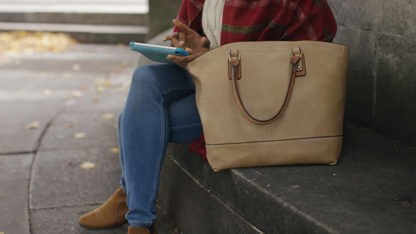Attractive young female outdoors using a digital tablet, with space for text