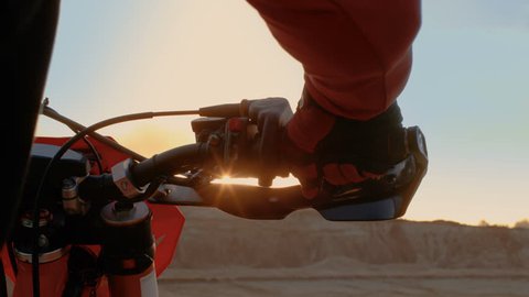 Close-up of the Motorcyclist's Hand Twisting Throttle Handle While Standing on the Scenic Quarry Off-Road Terrain in the Sunset. Shot on RED EPIC-W 8K Helium Cinema Camera.