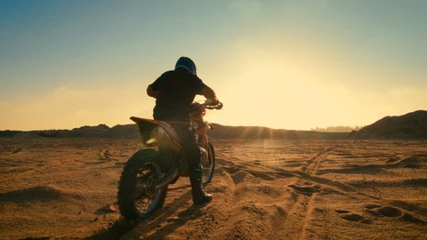 Following Shot of the Professional Motocross Driver Riding on His FMX Motorcycle on the Extreme Off-Road Terrain Track. Shot on RED EPIC-W 8K Helium Cinema Camera.