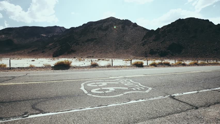 Car passing by Route 66 Sign on pavement
