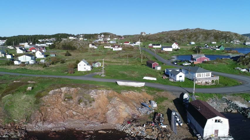 A beautiful aerial shot of ice bergs floating in the ocean water by an island at sunset off the coast of Twillingate Newfoundland Canada