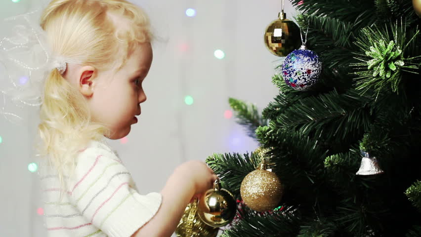 Little blonde girl decorates the Christmas tree