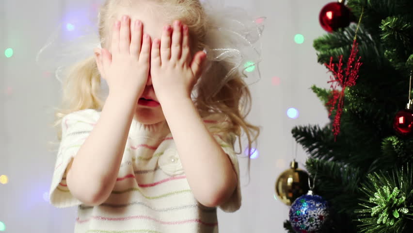 little girl near the Christmas tree waiting for a surprise