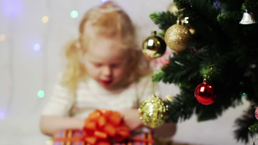 beautiful little girl gets a Christmas gift and runs away with it. rack focu. 