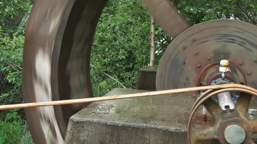 Pulley and belt driving a grindstone, waterwheel powered.