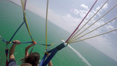 4k Air-to-air footage of paraglider tandem flying above sea pulled by motorboat yacht