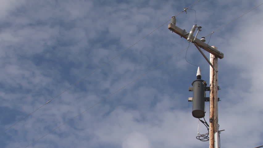 A moderate time-lapse of clouds in blue sky moving past a power pole with