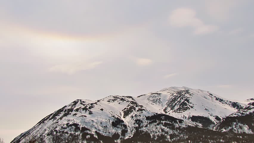 pearly light and a sun dog in the skies over an Alaskan mountain with wispy