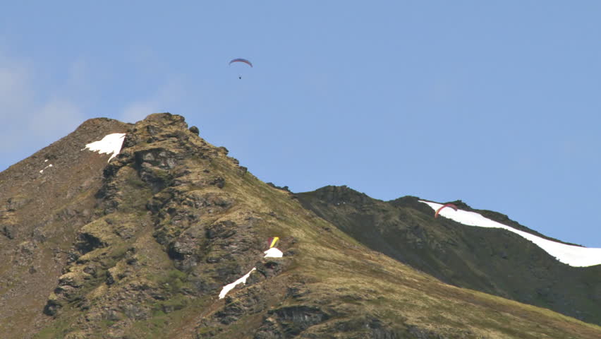 Several paragliders soaring gracefully on updrafts in the Talkeetna Range of