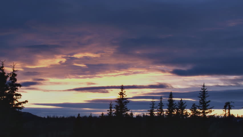Muted hues and subtle cloud shifts during sunset over forest in late spring