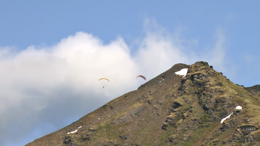 Paragliders soaring gracefully above the mountain ridges of Hathcer Pass in the