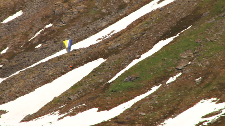 Paraglider gliding smoothly past a steep mountain slope makes a turn at Hatcher