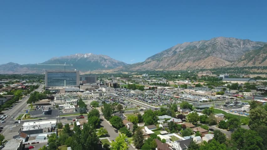Aerial over city parking lots and mountain background in a growing small town.