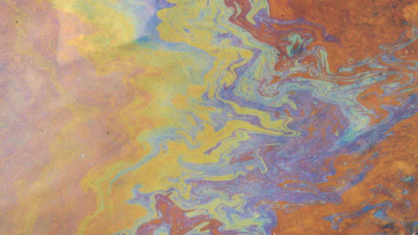 Toxic petroleum-based film on puddle, blown by wind.