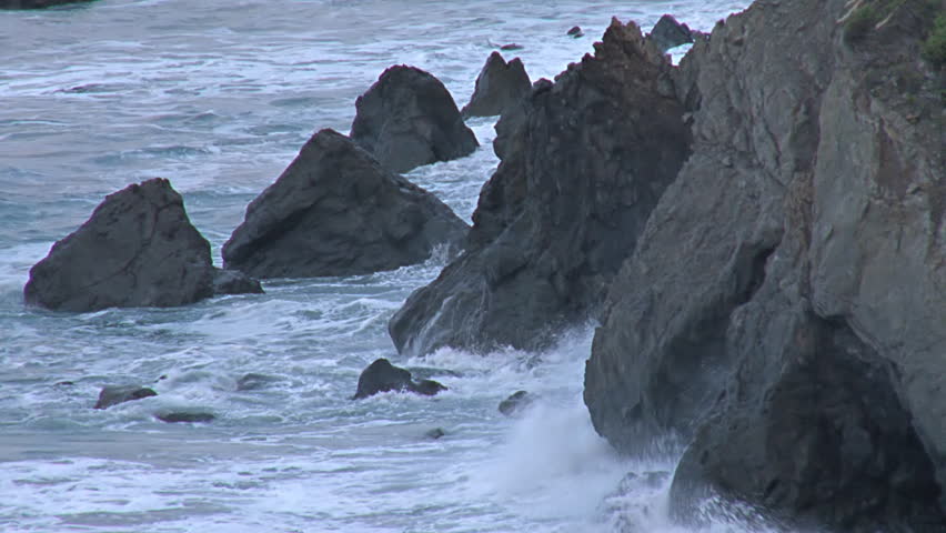 Pacific Ocean breakers crashing against the rocky bluff at high tide in the