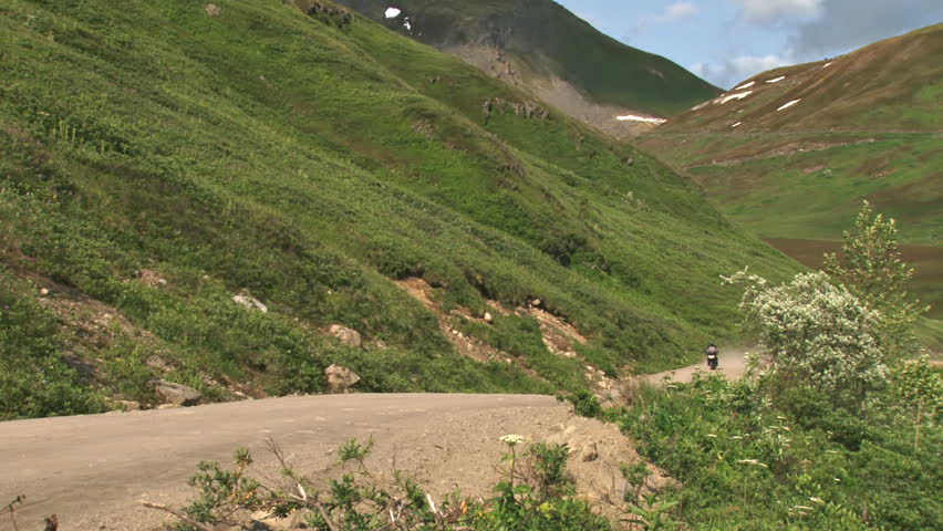 Motorcyclist touring Alaska passes by on an enduro road bike, suited for rough