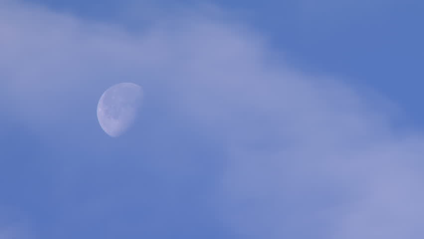 Waning gibbous moon moving through the sky with clouds rushing past.