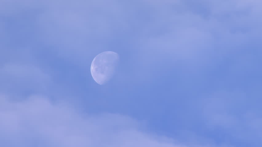 Waning gibbous moon partially obscured by fast-moving clouds. Time lapse.