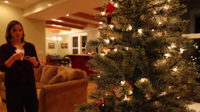 A woman decorates a small christmas tree in a house