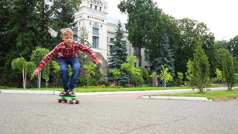 White child learning to skate on green plastic rollerskate in city street. Kid of 10 years has fun on summer or autumn evening. Real time full hd video footage.