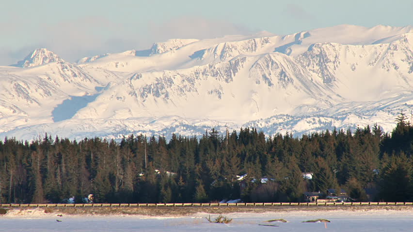 Flow of traffic, long shot, with scenic mountains beyond, in winter.