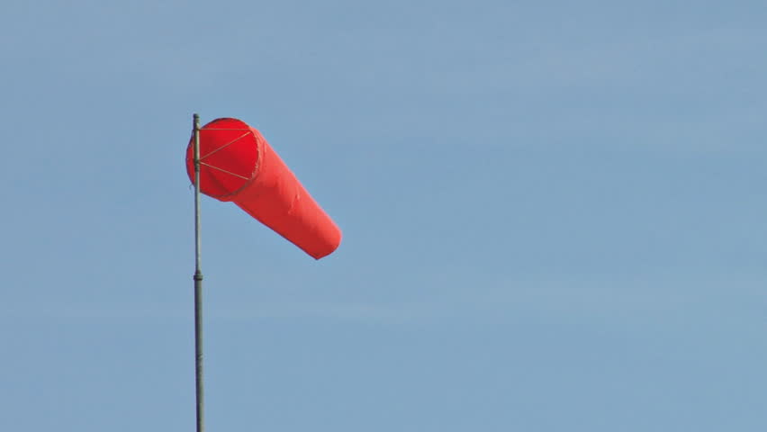 Windsock in moderate and fairly constant breeze. The sky beyond has a mild haze