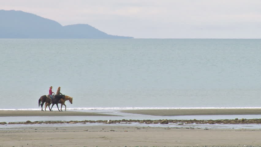 Two Women Riding Horses on the Beach