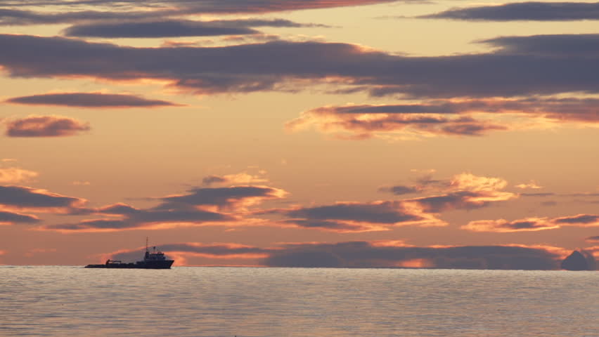 Utility Tug Ship Passing on Horizon During Sunset Clouds
