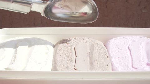 Three-colored ice cream being scooped out of container by a metal spoon. 4k