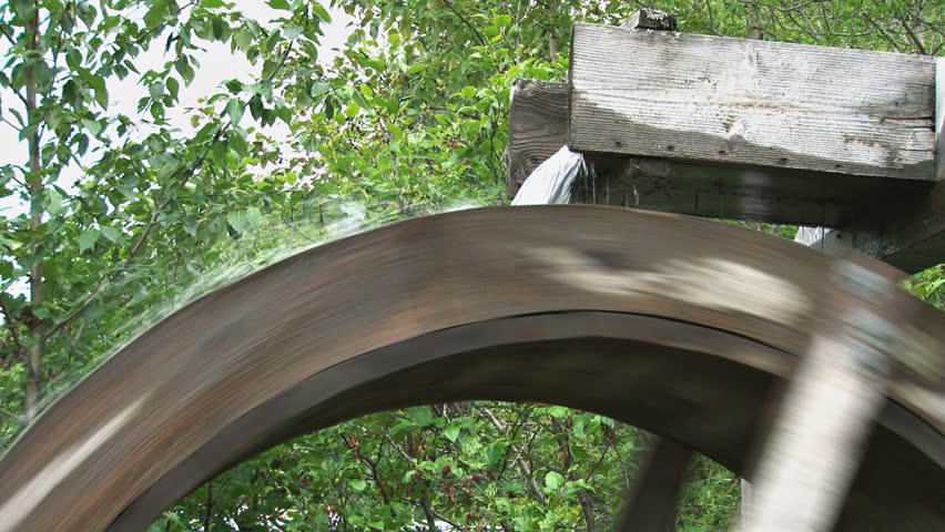 Close-up of the water pouring from the sluice of a turning waterwheel.