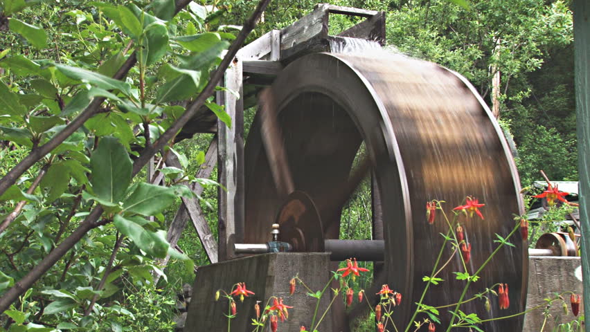 Rustic overshot waterwheel that runs a belt-driven grindstone.