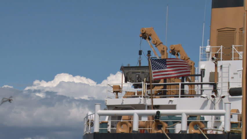 The United States flag flies from the superstructure of a Coast Guard cutter at