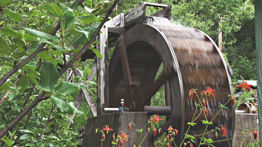 Rustic overshot waterwheel that runs a belt-driven grindstone. Blooming
