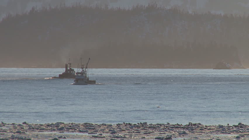 Tugboat and fishing boat passing each other out in the bay on a bright hazy