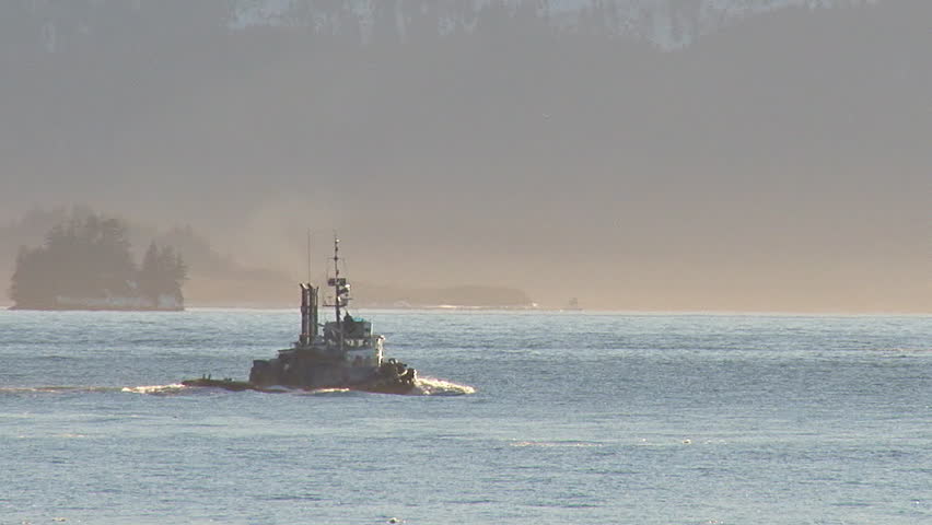 Tug boat redoubt heading out to sea on a misty hazy afternoon in the winter.