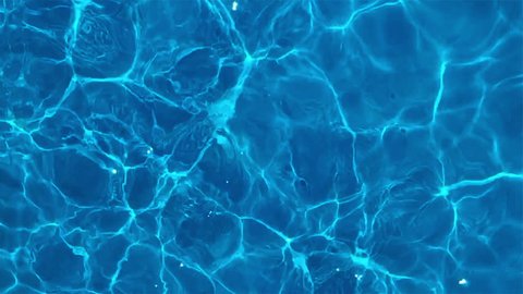 Pure blue water in the pool with light reflections. Slow motion.