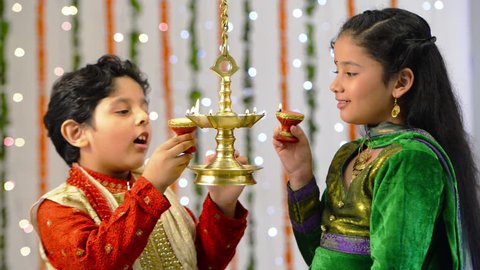 Locked-on shot of two children lighting an oil lamp during Diwali festival: film stockowy