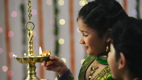 Locked-on shot of two children lighting an oil lamp during Diwali festival