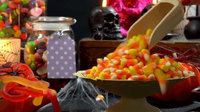Happy Halloween trick or treat party table with bowls and apothecary jars of candy with skull candles against a black background, scooping candy close up. - Powered by Shutterstock - Get 15% off with code: PIKWIZARD15