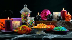 4k Happy Halloween trick or treat party table with bowls and apothecary jars of candy with skull candles against a black background, full table static. - Powered by Shutterstock - Get 15% off with code: PIKWIZARD15