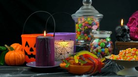 4k Happy Halloween trick or treat party table with bowls and apothecary jars of candy with skull candles against a black background, dolly slider shot. - Powered by Shutterstock - Get 15% off with code: PIKWIZARD15