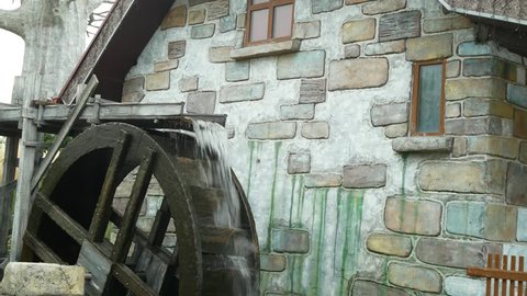 A large wooden wheel of a water mill spins, pumping water. 4k.
